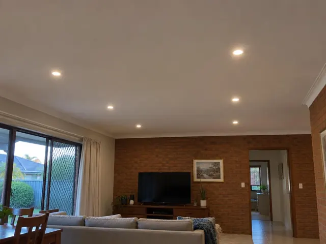 Living room ceiling with recessed downlights above brick feature wall and sofa in Ashmore
